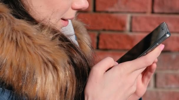 Närbild kvinnans händer bläddra internetsidor på mobiltelefon sitter i parken. — Stockvideo