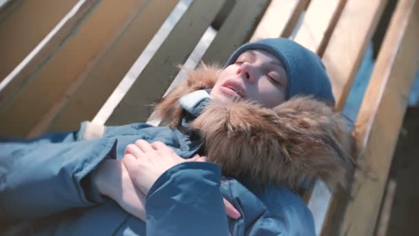 Γυναίκα αρρώστησε, ξαπλωμένη σε ένα παγκάκι στο χειμώνα, και να στενάζει. — Αρχείο Βίντεο
