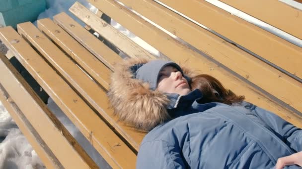 Tired young woman fall asleep in the Park on a bench in the winter. — Stock Video