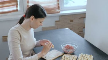 Kadın kıyma etli köfte yapar, kamera ve gülümsüyor görünüyor.