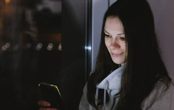 Женщина Просматривает Паутину Мобильном Телефоне Сидя Подоконнике Темную Ночь Дорожный — стоковое фото