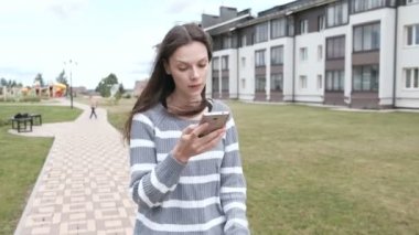 Güzel esmer kadın evinizin yakınında gyro scooter üzerinde haddeleme cep telefonunda bir mesaj okuma.