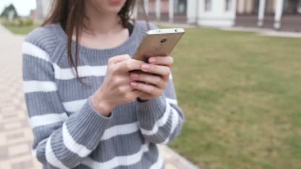 Unerkennbare brünette Frau liest etwas auf Handy, das in der Nähe der Wohnung läuft. — Stockvideo