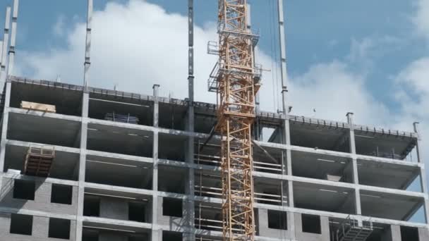 Edificio de varios pisos en construcción con una grúa de construcción sobre un fondo de cielo . — Vídeos de Stock