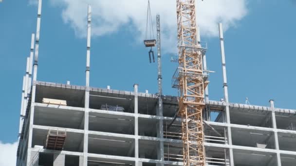 Multi-storey under construction appartment building with a working building crane on a sky background. — Stock Video