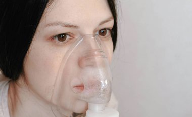 Nebulizatör ve astım tedavisi için kullanın. Portre genç kadının yüzü inhaler maskesi teneffüs edilmesi. Yan görünüm.