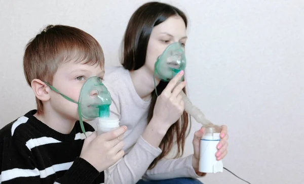 Use nebulizador e inalador para o tratamento. Mulher e menino inalando através da máscara do inalador. Vista lateral . — Fotografia de Stock
