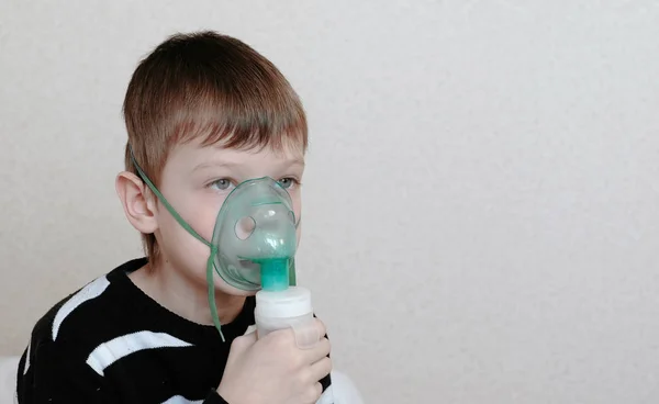 Use nebulizador e inhalador para el tratamiento. Niño inhalando a través de la máscara del inhalador. vista frontal — Foto de Stock