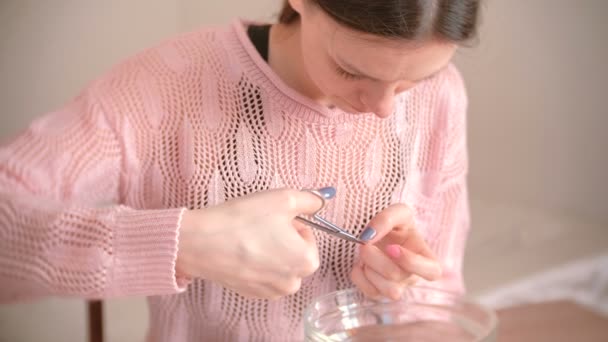 La mujer corta la cutícula con tijera y pinza. Hace la manicura ella misma. Herramientas de manicura sobre la mesa — Vídeos de Stock