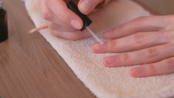 Vrouw zet een grondlaag van schellak op haar nagels. Close-up handen. — Stockvideo