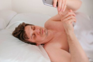 Brunet yakışıklı delikanlı uyanır ve onun cep telefonu alarmı kapatır.