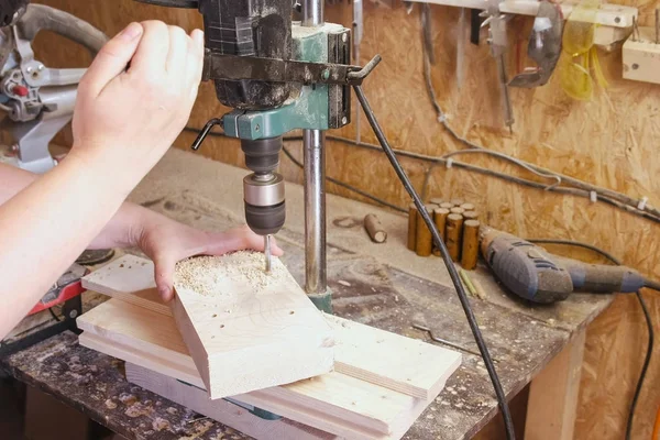 Travailleur perce des trous dans les modèles en bois. Fabrication de jouets en bois. Gros plan mains . — Photo