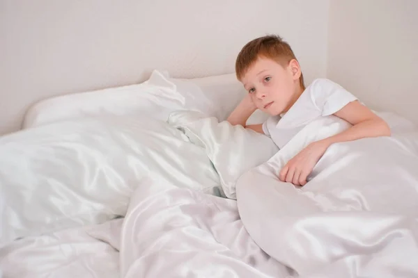 Sette anni ragazzo si sveglia nel suo letto sotto la coperta — Foto Stock