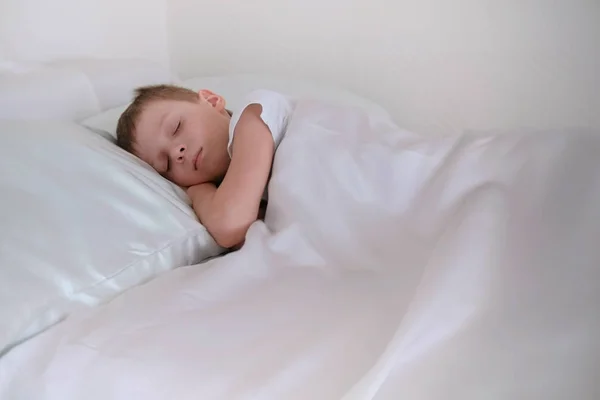 Menino de sete anos envolveu-se em um cobertor e dorme . — Fotografia de Stock