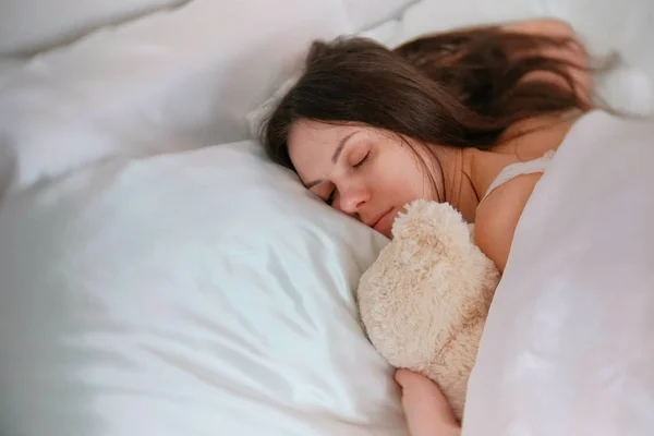 Jovem dormindo com um urso de brinquedo . — Fotografia de Stock