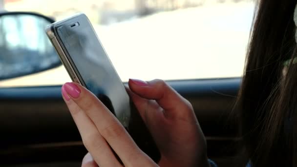Close-up dames handen messaging haar mobiel in de auto zit. Zijaanzicht. — Stockvideo