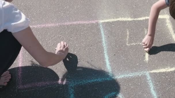 Mother and son draw numbers two and three on the hopscotch on asphalt. — Stock Video