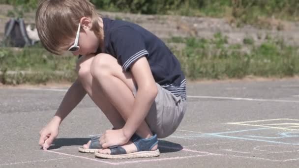 Il ragazzo sta disegnando della tramoggia sull'asfalto. Vista da vicino . — Video Stock