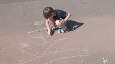 Çocuk bir gemi Mavi Tebeşir ile asfalt üzerine çizer. Yakın çekim yakışıklı.