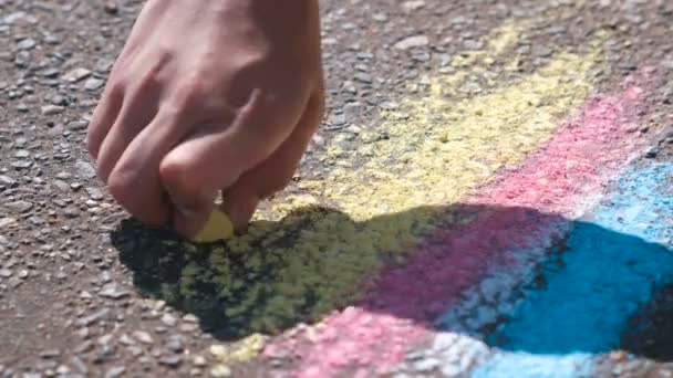 Pojke ritar med blå krita på asfalten. Närbild händer. — Stockvideo