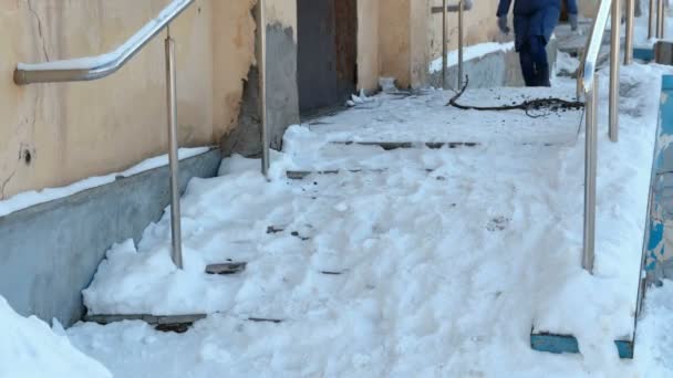 Escaleras resbaladizas. Mujer irreconocible con una chaqueta azul bajando por una escalera nevada . — Vídeo de stock