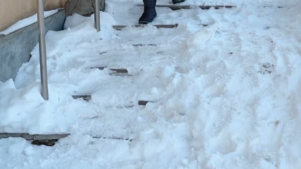 Escaleras resbaladizas. Mujer irreconocible con una chaqueta azul bajando por una escalera nevada . — Vídeo de stock