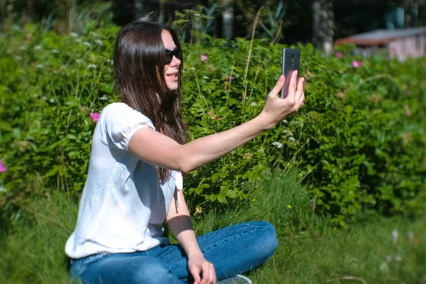 Mujer blogger habla en video chat, disparándose a sí misma en un teléfono móvil, video selfie . — Foto de Stock