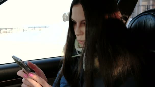 Detail žena chatování její mobil a usmívá se, sedí v autě. Boční pohled. — Stock video