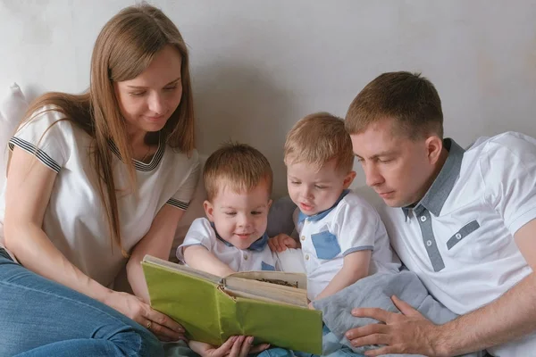 Family mom, dad and two twin brothers read books laying on the bed. Family reading time. — Stock Photo, Image