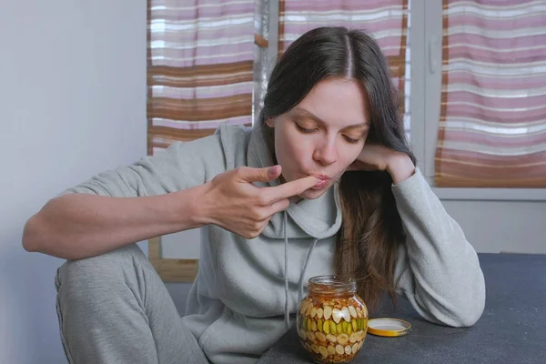 La mujer sumerge su dedo en miel con nueces en el frasco. Come miel del dedo . — Foto de Stock