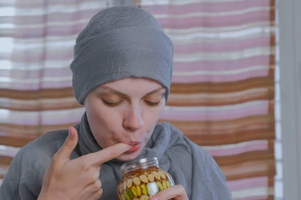 Mujer musulmana en un pañuelo en la cabeza sumerge su dedo en miel con nueces en el frasco. Come miel del dedo . — Foto de Stock