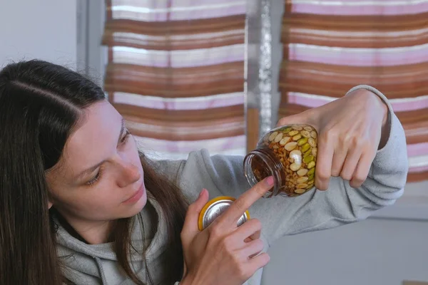 Женщина ест мед из банки орехов в меду пальцем . — стоковое фото