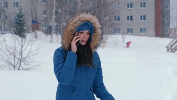Νεαρή όμορφη γυναίκα που μιλάμε στο τηλέφωνο σε εξωτερικούς χώρους σε χιονοπτώσεις το χειμώνα. — Αρχείο Βίντεο