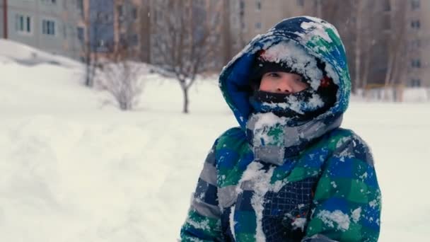 Junge wirft Schnee und bringt Schneefall, spielt im Winter im Schnee. — Stockvideo