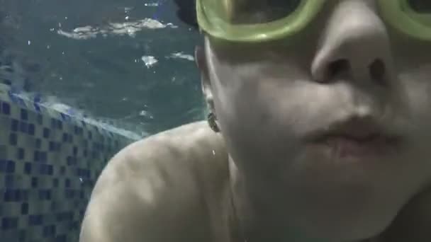 Vrouw is onderwater zwemmen. Close-up womans portret in googles. — Stockvideo