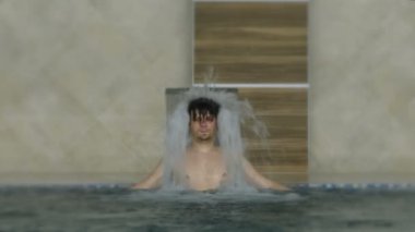 Havuzu spa gün zevk rahatlatıcı tatil beldesinde bir genç adam. Hidro masaj boyun ağrısı için. Altında su jet, boyun ve omurga masajı rahatlatıcı.
