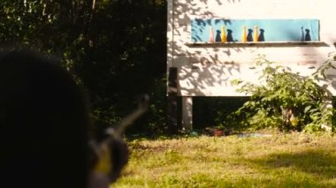 Kadın silah vuruyor ve hedefi vurur. Arkadan görünüm.