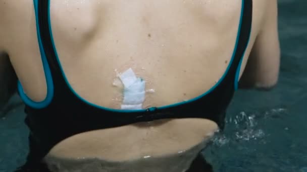 Patch impermeável na parte de trás de uma mulher. Mulher irreconhecível nadando na piscina . — Vídeo de Stock