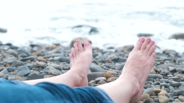 妇女脚在牛仔裤对海在石头海滩. — 图库视频影像