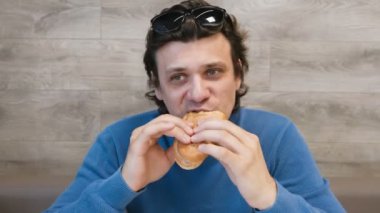 Adam bir hotdog kafede yiyor.