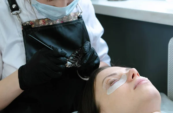 Tratamiento de belleza. El cosmetólogo pone pintura negra en las pestañas. Botox y pestañas laminadas . — Foto de Stock