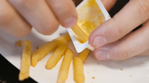 Ο άνθρωπος τρώει πατάτες τηγανιτές με σάλτσα τυριού. Χέρια γκρο πλαν. — Αρχείο Βίντεο