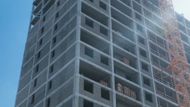 Mehrstöckige im Bau befindliche Gebäude und Baukran vor dem Hintergrund des klaren Himmels. Nahaufnahme. — Stockvideo