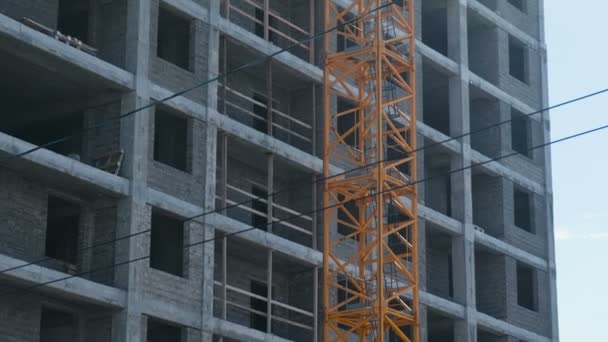 Flera våningar under byggandet byggnad och konstruktion kran på bakgrunden av klar himmel. Närbild. — Stockvideo