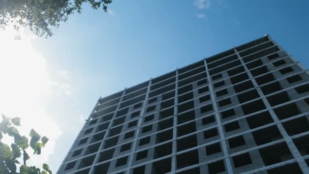 Multi-storey under construction building and construction crane on clear sky background. — Stock Video