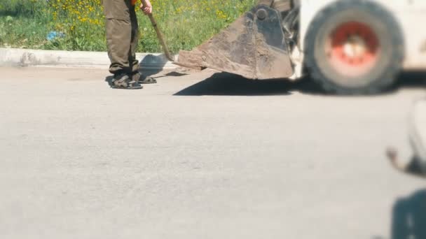 Kent içi temizlik. Adam bir kürekle kir toplar ve her şeyi Ekskavatör kova içine atar. Bacaklar yakın çekim. — Stok video