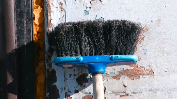 Broom against the wall with peeling plaster. — Stock Video