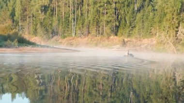 Balıkçı bir hava ile şişirilen motorlu tekne üzerinde nehir banka yüzer. Sonbahar orman içinde belgili tanımlık geçmiş.