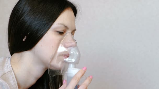 Use nebulizador e inhalador para el tratamiento. Las mujeres de primer plano se enfrentan a la inhalación a través de la máscara del inhalador. Vista lateral . — Vídeos de Stock