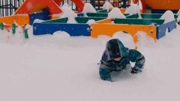 Αγόρι που σέρνεται μέσα από το πολύ χιόνι στην παιδική χαρά. — Αρχείο Βίντεο